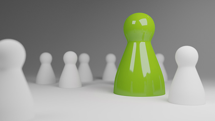 Mit Mehrwert aus der Masse herausstechen Eine grüne Spielfigur unter vielen weißen stellt symbolisch den Mehrwert dar